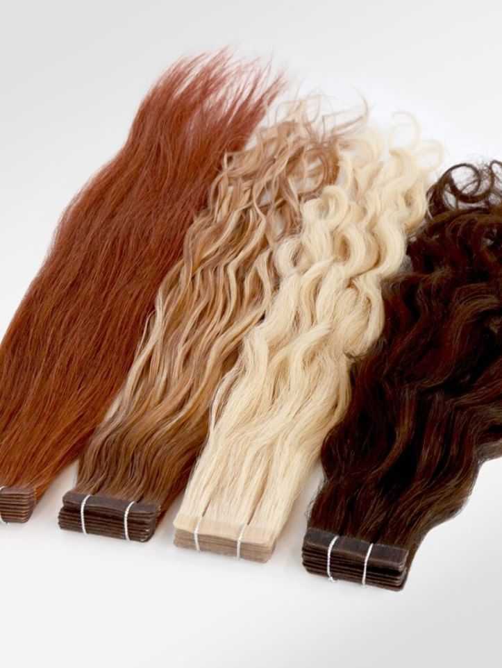 Various shades of wavy hair extensions: auburn, blonde, and dark brown, displayed side by side.
